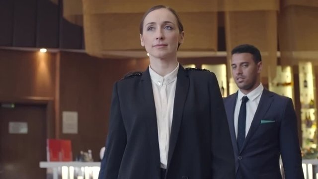 Confident businesswoman walking through hotel lobby with two male colleagues following her