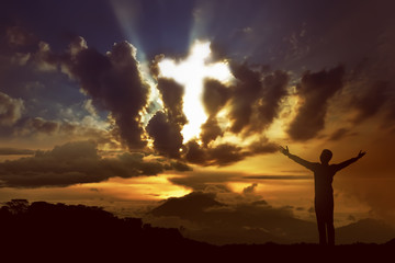 Man praying to god with ray of light shaping cross on the sky © Leo Lintang