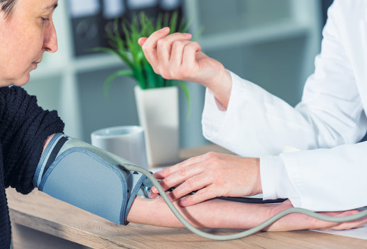 Doctor cardiologist measuring blood pressure of female patient