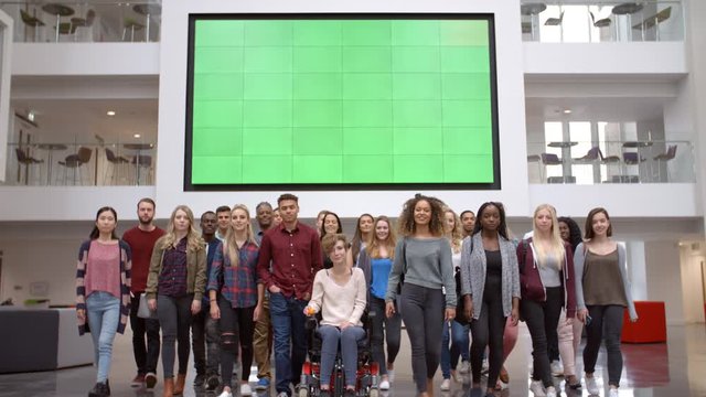 Large group of students walk to camera in university atrium