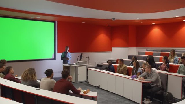 Teacher at lectern listening to students in lecture theatre