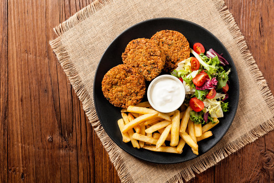 Serving of falafel and chips served on a black plate with sauce.
