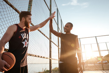 Sportsmen giving high five while playing basketball at the playground