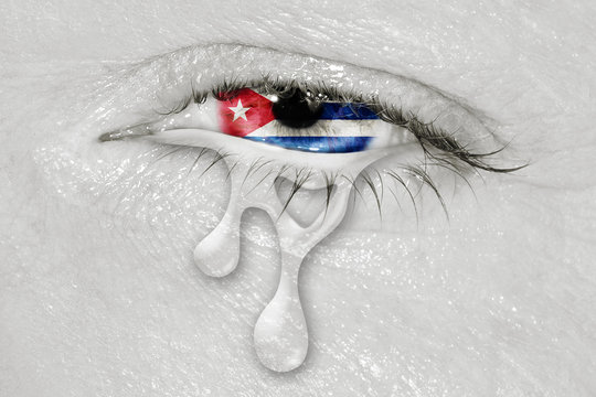 Crying eye with Cuba Flag iris on black and white face. concept of sadness for Cuba, patriotic metaphor.