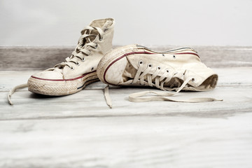 Old white sneakers on wooden background