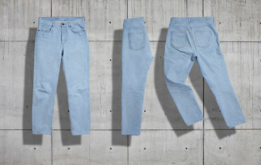 Classic light blue womens jeans shot as a set from the front, back and folded in half on industrial concrete background