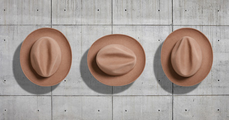 Classic felt beige fedora hat shot from the top in three different rotations as a set isolated neutral gray concrete industrial background