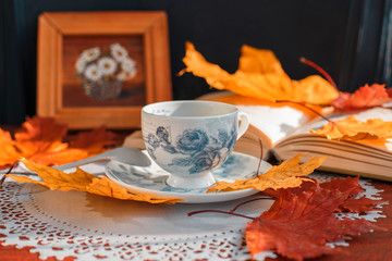 Naklejka na ściany i meble coffee Cup and book on a table on a background of yellow leaves