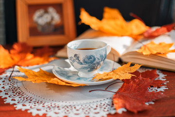coffee Cup and book on a table on a background of yellow leaves