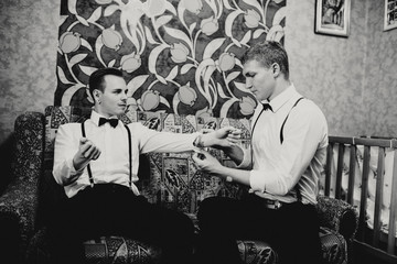 Groomsman is helping to dress up to the groom