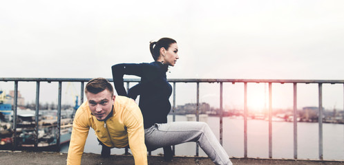 Couple young athletes in sportswear are training on the Sunset