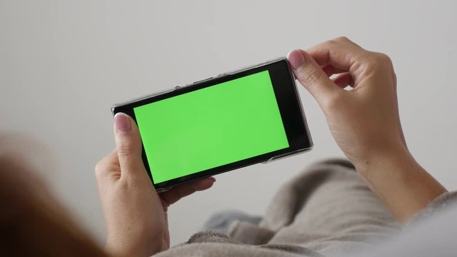 Female holding green screen smart phone while in bed 4K 2160p 30fps UHD footage - Modern redhead woman with chroma key greenscreen tablet 3840X2160 UltraHD video
