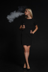 woman in a black dress smokes an electronic cigarette