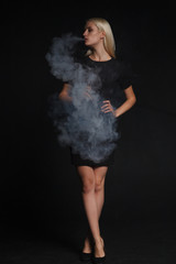woman in a black dress smokes an electronic cigarette