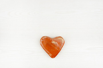 Ceramic heart isolated on white wooden background. Decorative red heart top view.