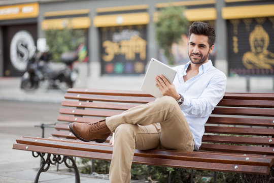 Young man sitting on bench with laptop
