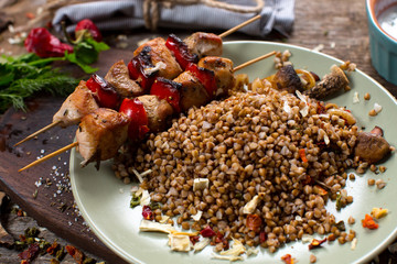 Buckwheat with sauce and chicken kebabs on skewers on a plate