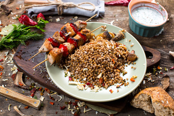 Buckwheat with sauce and chicken kebabs on skewers on a plate