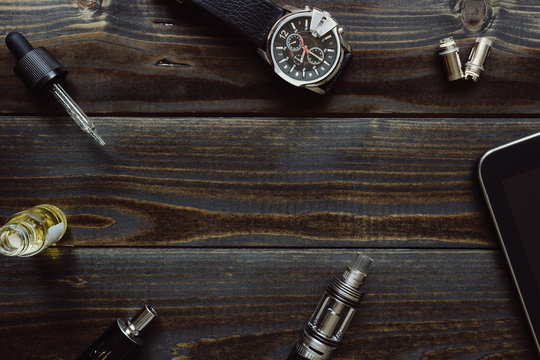 Vaping set, watch and tablet on the dark table. Hipster or bussi
