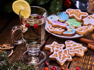 Christmas cookies on plate under fir branches. Christmas still life with mug decoration lemon slice hot drink on wooden table.