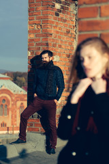 Young couple near roof brick wall