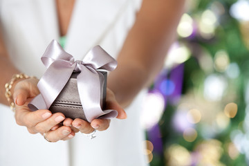 Female hands holding small elegant gift with ribbon.