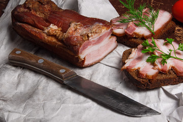 Smoked bacon with rye black bread and cuted tomatoes on the pack