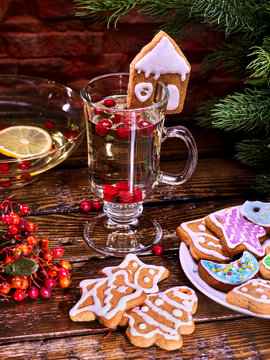 Christmas glass latte mug and Christmas multicolored cookies on plate with fir branches. Mag decoration cookie in form of house on wooden table in restaurant.