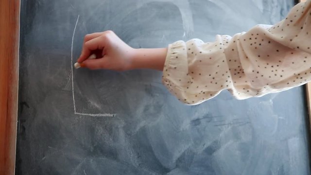 Girl writing E=MC2 on blackboard