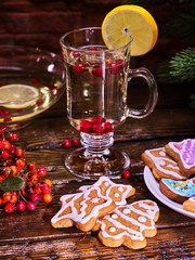 Christmas glass latte mug and Christmas multicolored cookies on plate with fir branches. Mag decoration lemon slice on wooden table in restaurant.