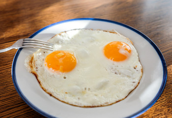 Fried eggs like a smily face on the tray with the light blue platter
