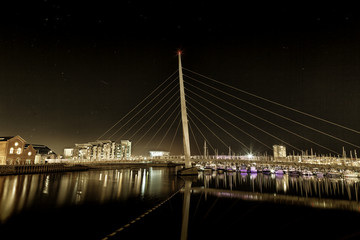 Fototapeta na wymiar Swansea Sail Bridge Night time at the River Tawe and the Millennium bridge in Swansea
