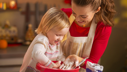 Mother and baby playing while making christmas cookies in kitche © Alliance