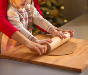 Obraz na płótnie Canvas Smiling mother and baby rolling pin dough in christmas decorated