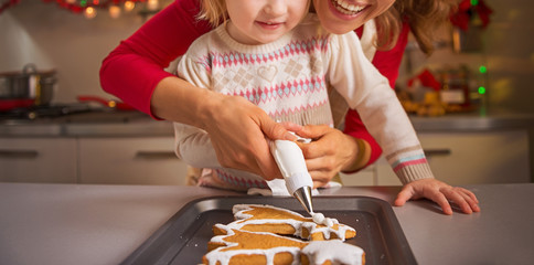 Happy mother and baby decorating homemade christmas cookies with - obrazy, fototapety, plakaty