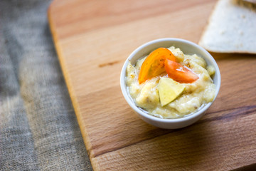 Delicious hummus on wooden board with the vegatables and pieces of bread.