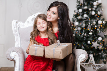 happy family mother and daughter in red dress with Christmas present in the home

