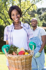 Obraz premium Young woman holding a basket of freshly harvested vegetables