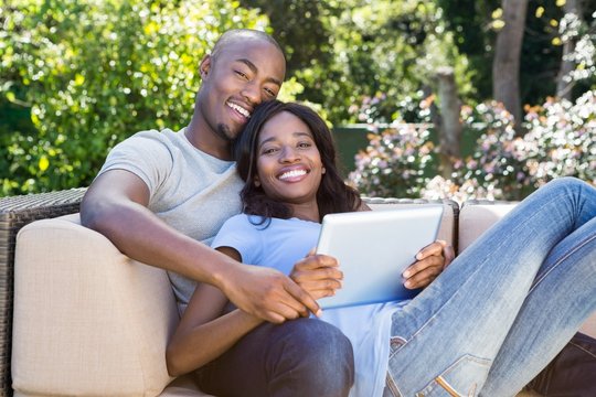 Young Couple Relaxing On The Sofa And Using Digital Tablet