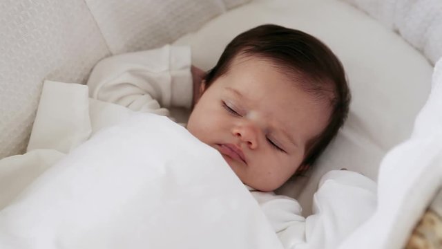 Sleepy baby girl in bassinet