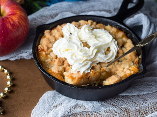 Apple crumble with cream in skillet. Closeup