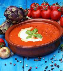 Tomato, red pepper soup, sauce with olive oil, rosemary and smoked paprika on a wooden background.