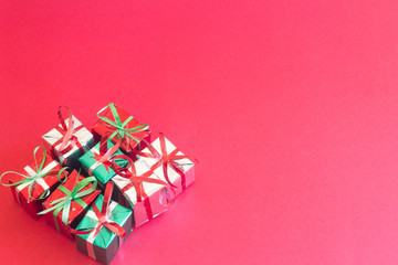 Christmas gift box with green leaves on red color background for