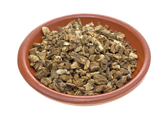 Dried cut and sifted burdock root in a small bowl isolated on a white background.