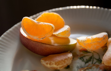 slices of mandarin and apple on a plate close-up