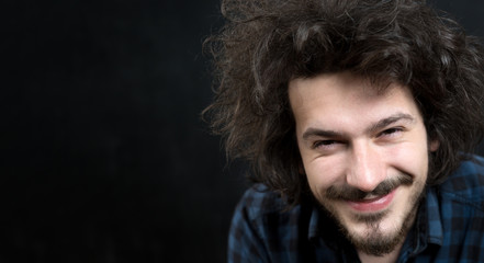 Portrait of a fashionable young man with funny hair on dark back