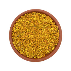 Bowl of bee pollen granules on a white background top view.