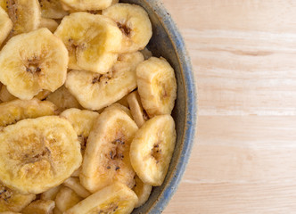 Dried bananas in an old bowl on a table top close view.