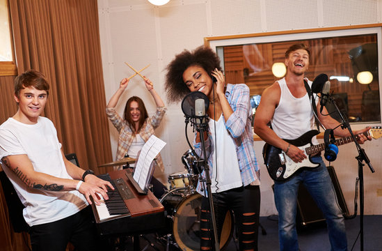 Multiracial music band performing in a recording studio  - Powered by Adobe