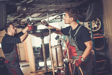 Profecional car  mechanic changing motor oil in automobile engin
